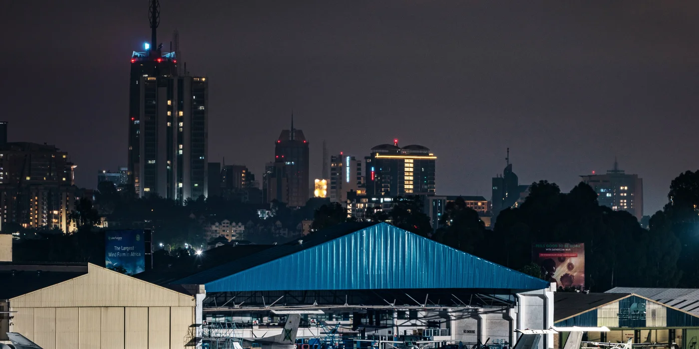 Wilson Airport hangars and Nairobi city skyline at night, Barguts Tours airport transfer coverage.