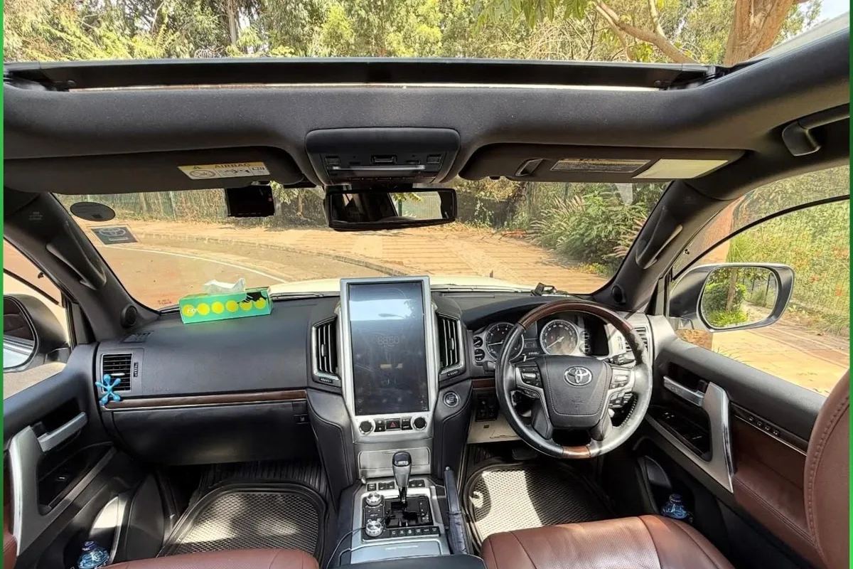 Open sunroof above the dashboard and tan leather seats of a Toyota Land Cruiser V8