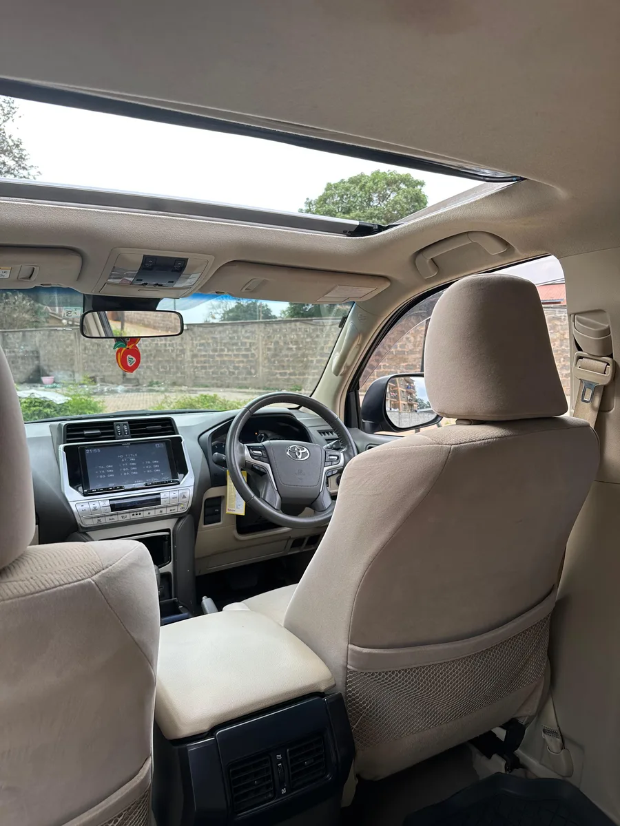 Open sunroof above the cream front seats of a Toyota Prado TX