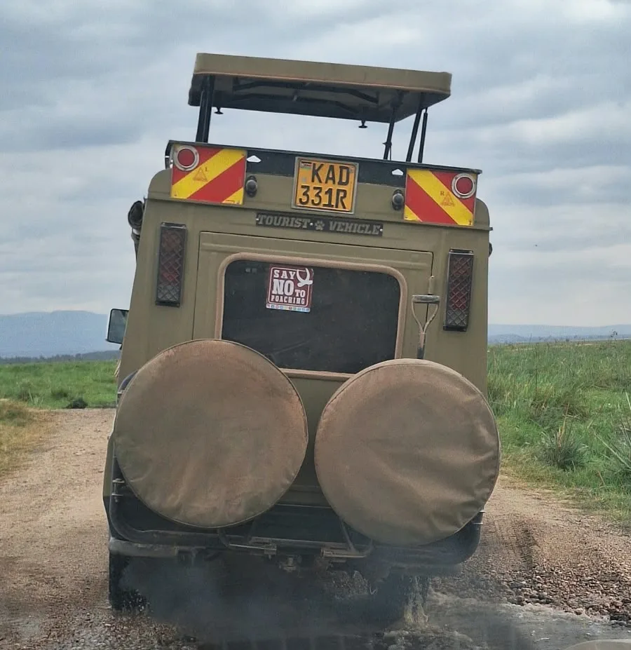 Olive Toyota Land Cruiser safari vehicle with its pop-up roof raised on a murram game-drive track